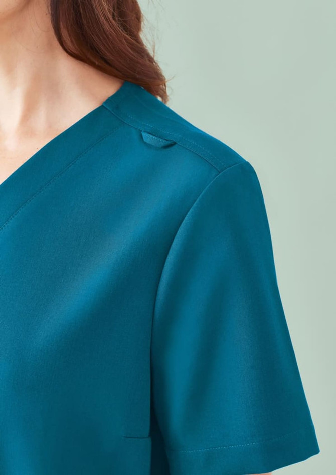 A close-up of a women's teal V-neck scrub top featuring short sleeves and a small shoulder detail.