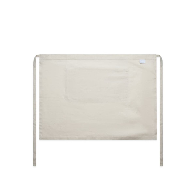 A beige linen half apron featuring a front pocket and ties for fastening, with a logo on the side.