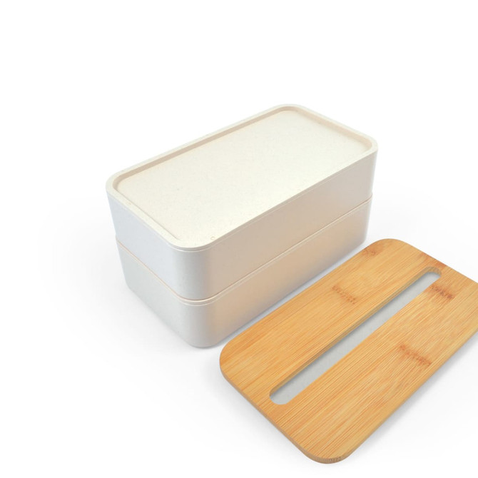 A two-tiered lunch box in cream color with a bamboo lid designed to hold a phone. It features a simple logo.