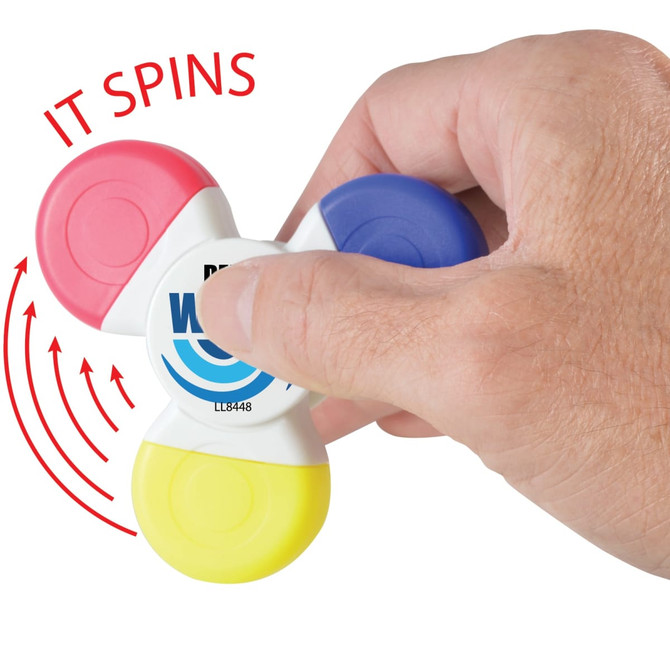 A Spinner Highlighter with red, blue, yellow, and pink sections, held in a hand, featuring the text "IT SPINS".