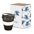 A drink bottle in black with a white band, next to a floral-patterned box. The bottle has a lid and a logo.