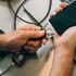 A braided charging cable in black with multiple connectors, held in one hand while a smartphone is in the other hand.