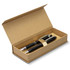 A kraft gift box containing two black pens with silver accents, featuring a simple logo on the lid.