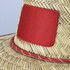 A Tiki straw hat featuring a natural straw body with a red band and a red patch on the front.
