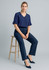 A woman sits on a stool wearing navy blue cool stretch adjustable waist pants and a matching navy top.