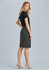 A woman stands wearing a grey pleated skirt and a black top, showcasing a sleek, professional look.
