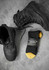 A pair of black work boots alongside a black and yellow sock with a logo.