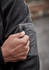 A close-up of a hand adjusting the zipper on a black water-resistant hoodie, showing droplets of water on the fabric.