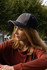 A two-tone cap in grey with contrasting navy stitching, featuring an open lip sandwich design and a logo.