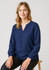 A navy long sleeve blouse with a V-neck and gathered sleeves, worn by a seated model.