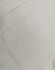 A close-up of a light-coloured cotton blend shirt featuring a back pocket and a button detail.