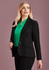 A black mid-length women's jacket is styled with a green blouse. The jacket features a fitted design and has a logo.