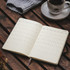 A Moleskine 2027 planner with a cream-coloured interior, opened to show weekly layouts, next to a cup of coffee.