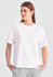 A white box tee featuring short sleeves, worn by a model, paired with grey trousers. Includes a logo.