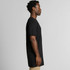 A side view of a black Tall Tee t-shirt, showcased on a model with short, curly hair. The shirt has a relaxed fit.
