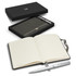 A grey notebook with lined pages and a silver pen, presented in a sleek black gift box with branding.