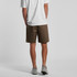 A person stands with their back to the camera, wearing olive green Walk Shorts and grey shoes.