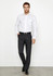A man poses in a white shirt and dark grey classic flat pants, with a belt and sleek shoes, against a plain background.