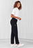 A woman wearing black women's cargo pants paired with a white shirt and white sneakers, standing on a light background.