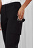 A pair of black women's cargo pants featuring side pockets and a logo, with a hand reaching for a phone.