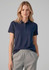 A woman wearing a navy short sleeve polo shirt, paired with light grey sweatpants, with a logo on the shirt.