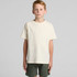 A neutral cream youth T-shirt with short sleeves, paired with dark green shorts. The shirt features a logo.
