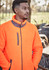 A man wearing an orange unisex full zip sherpa fleece, featuring a high collar and zippered front pockets.
