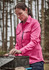 A long sleeve women's button-up shirt in pink, featuring chest pockets, worn outdoors among trees.