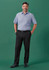 A man in a light blue short-sleeve shirt and black adjustable waist straight leg pants stands against a green backdrop.