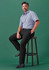 Men's straight leg pants in black, worn by a model seated on a stool. The model is dressed in a blue shirt and black shoes.