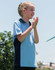 A light blue and navy polo shirt on a smiling child, with a logo on the chest.