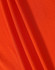 A close-up of orange fabric featuring a textured surface, ideal for polo shirts. The image includes a logo.