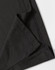 A close-up of a black polo shirt featuring a neatly stitched hem and collar. The fabric texture is visible.