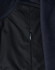 A close-up of a navy blue softshell jacket, featuring a zippered pocket and textured fabric.