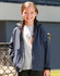 A girl wearing a navy blue softshell full zip hoodie over a grey top, smiling at the camera.