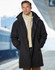 A man wearing a long black stadium jacket with a high collar, paired with a cream scarf.