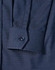 A navy blue pin dot stretch long sleeve shirt with a buttoned cuff and a branded logo.