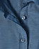 A close-up of a blue pin dot stretch 3/4 sleeve shirt featuring buttons and a fabric texture.