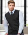 A dark grey Merino wool V-neck vest worn over a light blue shirt and tie, featuring a subtle logo.