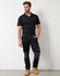 A black short-sleeve polo shirt worn with dark trousers and work boots, featuring a logo on the shirt.
