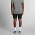 Active shorts in black viewed from the back, paired with a grey t-shirt and athletic shoes. Features a logo.