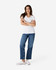 A model wearing a white Gildan Softstyle Ladies' V-Neck T-Shirt paired with blue jeans and white sneakers.