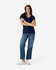 A woman is wearing a navy Gildan Softstyle ladies' V-neck T-shirt, paired with blue jeans and white sneakers.