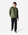 A green Gildan Softstyle adult sweatshirt worn by a model, paired with dark pants and black sneakers.