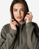 A hooded sweatshirt in earthy green, featuring a drawstring hood and a plain design. It includes a logo.