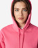 A pink hooded sweatshirt with a drawstring, featuring a hood and a simplistic design, is displayed on a model.
