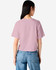 A back view of a pink boxy t-shirt with short sleeves, paired with light blue denim jeans. The shirt features a logo.