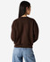 A women's crewneck sweatshirt in brown, featuring a relaxed fit and a logo. The model is shown from the back.
