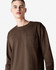 A model wears a brown American Apparel Super Heavyweight T-Shirt with a chest pocket. The image features a logo.
