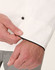 A close-up of a white executive chef jacket featuring black piping, highlighting the cuff detail and button.